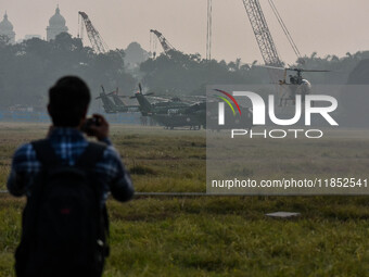 People watch Indian Army helicopters during a practice run for the upcoming Vijay Diwas celebrations in Kolkata, India, on December 10, 2024...