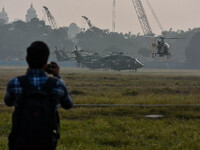 People watch Indian Army helicopters during a practice run for the upcoming Vijay Diwas celebrations in Kolkata, India, on December 10, 2024...