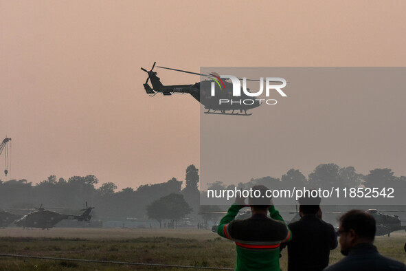 People watch Indian Army helicopters during a practice run for the upcoming Vijay Diwas celebrations in Kolkata, India, on December 10, 2024...