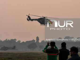 People watch Indian Army helicopters during a practice run for the upcoming Vijay Diwas celebrations in Kolkata, India, on December 10, 2024...