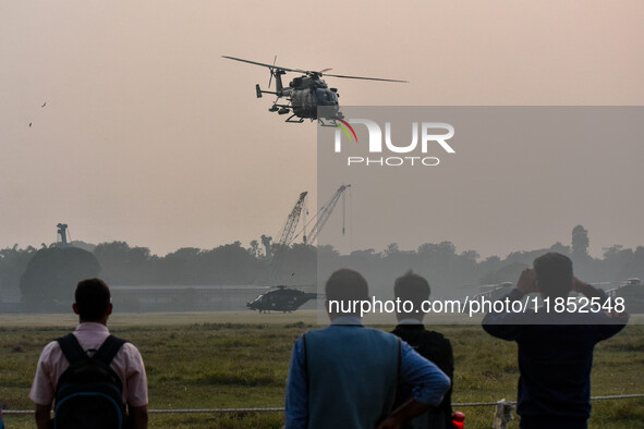 People watch Indian Army helicopters during a practice run for the upcoming Vijay Diwas celebrations in Kolkata, India, on December 10, 2024...