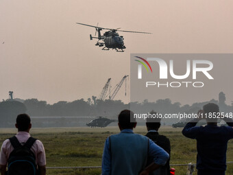 People watch Indian Army helicopters during a practice run for the upcoming Vijay Diwas celebrations in Kolkata, India, on December 10, 2024...