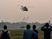 People watch Indian Army helicopters during a practice run for the upcoming Vijay Diwas celebrations in Kolkata, India, on December 10, 2024...