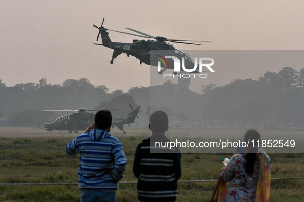 People watch Indian Army helicopters during a practice run for the upcoming Vijay Diwas celebrations in Kolkata, India, on December 10, 2024...