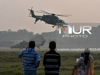 People watch Indian Army helicopters during a practice run for the upcoming Vijay Diwas celebrations in Kolkata, India, on December 10, 2024...