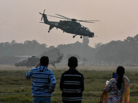 People watch Indian Army helicopters during a practice run for the upcoming Vijay Diwas celebrations in Kolkata, India, on December 10, 2024...