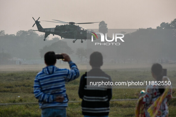 People watch Indian Army helicopters during a practice run for the upcoming Vijay Diwas celebrations in Kolkata, India, on December 10, 2024...