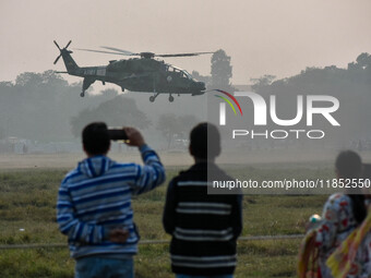 People watch Indian Army helicopters during a practice run for the upcoming Vijay Diwas celebrations in Kolkata, India, on December 10, 2024...