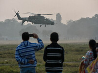 People watch Indian Army helicopters during a practice run for the upcoming Vijay Diwas celebrations in Kolkata, India, on December 10, 2024...