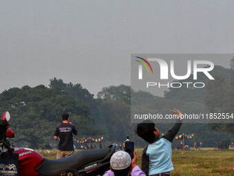 People watch Indian Army helicopters during a practice run for the upcoming Vijay Diwas celebrations in Kolkata, India, on December 10, 2024...