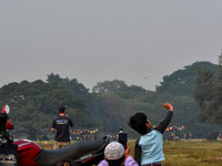 People watch Indian Army helicopters during a practice run for the upcoming Vijay Diwas celebrations in Kolkata, India, on December 10, 2024...