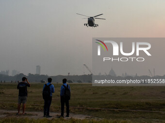 People watch Indian Army helicopters during a practice run for the upcoming Vijay Diwas celebrations in Kolkata, India, on December 10, 2024...