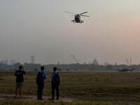 People watch Indian Army helicopters during a practice run for the upcoming Vijay Diwas celebrations in Kolkata, India, on December 10, 2024...