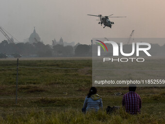 People watch Indian Army helicopters during a practice run for the upcoming Vijay Diwas celebrations in Kolkata, India, on December 10, 2024...