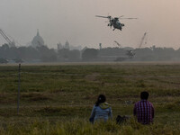 People watch Indian Army helicopters during a practice run for the upcoming Vijay Diwas celebrations in Kolkata, India, on December 10, 2024...