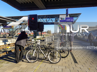 At Mühldorf station in Bavaria, Germany, on November 30, 2024, a small group of travelers waits patiently on the platform. The scene is calm...