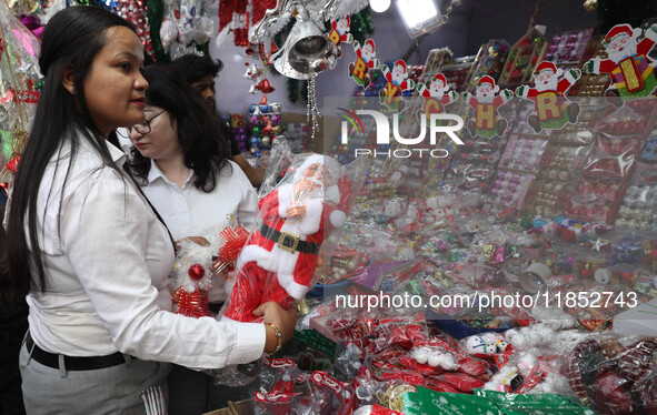 A woman buys a Santa Claus toy from a Christmas Market in Kolkata, India, on December 10, 2024. 