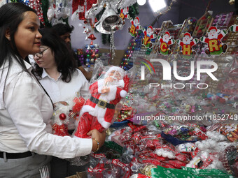 A woman buys a Santa Claus toy from a Christmas Market in Kolkata, India, on December 10, 2024. (