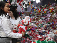 A woman buys a Santa Claus toy from a Christmas Market in Kolkata, India, on December 10, 2024. (