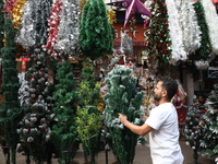 A vendor arranges a Christmas tree for sale at a Christmas Market in Kolkata, India, on December 10, 2024. (