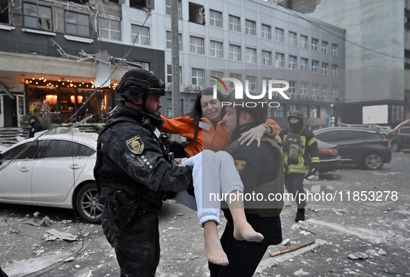 Police officers pass a woman rescued from a building destroyed by a Russian missile strike in Zaporizhzhia, Ukraine, on December 10, 2024. T...