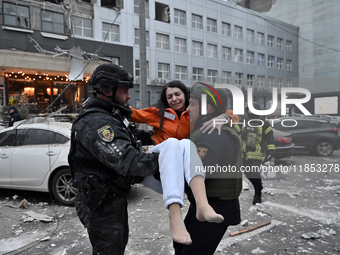 Police officers pass a woman rescued from a building destroyed by a Russian missile strike in Zaporizhzhia, Ukraine, on December 10, 2024. T...