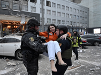 Police officers pass a woman rescued from a building destroyed by a Russian missile strike in Zaporizhzhia, Ukraine, on December 10, 2024. T...