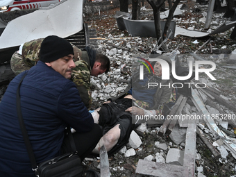 People stand by an elderly man injured by a Russian missile strike in Zaporizhzhia, Ukraine, on December 10, 2024. Three people are dead and...