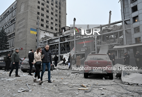 People stand outside a building destroyed by a Russian missile strike in Zaporizhzhia, Ukraine, on December 10, 2024. Three people die, and...