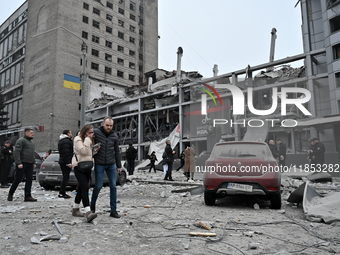 People stand outside a building destroyed by a Russian missile strike in Zaporizhzhia, Ukraine, on December 10, 2024. Three people die, and...