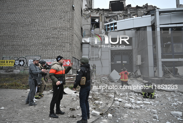 People stand outside a building destroyed by a Russian missile strike in Zaporizhzhia, Ukraine, on December 10, 2024. Three people die, and...