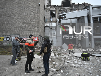 People stand outside a building destroyed by a Russian missile strike in Zaporizhzhia, Ukraine, on December 10, 2024. Three people die, and...