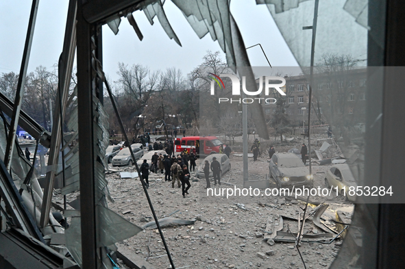 A broken window frames people in the street during a response effort to a Russian missile strike in Zaporizhzhia, Ukraine, on December 10, 2...