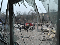 A broken window frames people in the street during a response effort to a Russian missile strike in Zaporizhzhia, Ukraine, on December 10, 2...