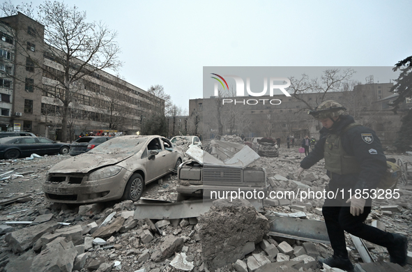 A police officer walks past cars crushed by the rubble after a Russian missile strike in Zaporizhzhia, Ukraine, on December 10, 2024. Three...