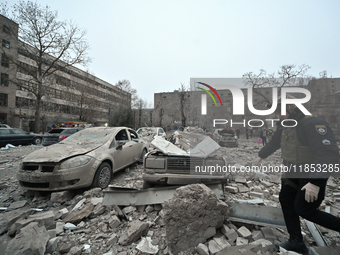 A police officer walks past cars crushed by the rubble after a Russian missile strike in Zaporizhzhia, Ukraine, on December 10, 2024. Three...