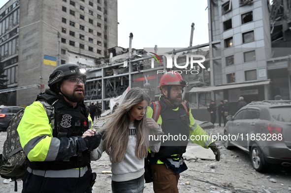 In Zaporizhzhia, Ukraine, on December 10, 2024, first responders support a woman as they walk past a building destroyed by a Russian missile...