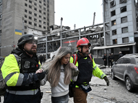 In Zaporizhzhia, Ukraine, on December 10, 2024, first responders support a woman as they walk past a building destroyed by a Russian missile...