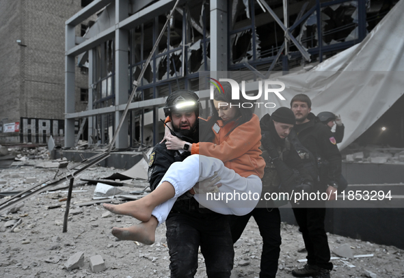 In Zaporizhzhia, Ukraine, on December 10, 2024, a police officer carries a woman rescued from a building destroyed by a Russian missile stri...