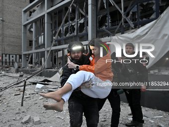 In Zaporizhzhia, Ukraine, on December 10, 2024, a police officer carries a woman rescued from a building destroyed by a Russian missile stri...