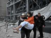 In Zaporizhzhia, Ukraine, on December 10, 2024, a police officer carries a woman rescued from a building destroyed by a Russian missile stri...