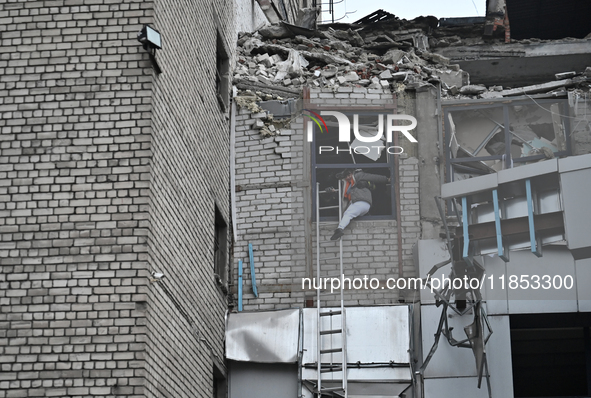 In Zaporizhzhia, Ukraine, on December 10, 2024, a woman tries to step onto a telescopic ladder as she exits a building damaged by a Russian...