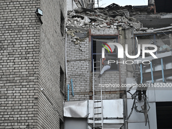 In Zaporizhzhia, Ukraine, on December 10, 2024, a woman tries to step onto a telescopic ladder as she exits a building damaged by a Russian...