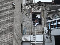 In Zaporizhzhia, Ukraine, on December 10, 2024, a woman tries to step onto a telescopic ladder as she exits a building damaged by a Russian...