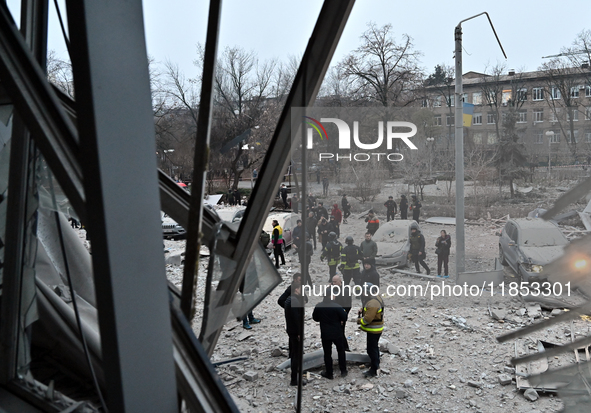 A broken window frames people in the street during a response effort to a Russian missile strike in Zaporizhzhia, Ukraine, on December 10, 2...