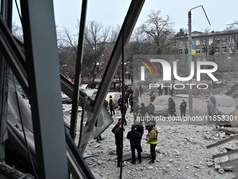 A broken window frames people in the street during a response effort to a Russian missile strike in Zaporizhzhia, Ukraine, on December 10, 2...