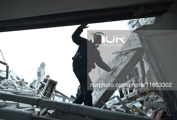 A police officer walks through the rubble into a building during a search and rescue operation after a Russian missile strike in Zaporizhzhi...