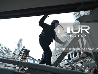 A police officer walks through the rubble into a building during a search and rescue operation after a Russian missile strike in Zaporizhzhi...