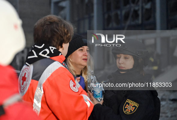 In Zaporizhzhia, Ukraine, on December 10, 2024, a Ukrainian Red Cross Society member and a police officer assist a woman crying near a build...