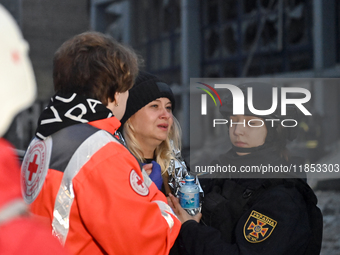 In Zaporizhzhia, Ukraine, on December 10, 2024, a Ukrainian Red Cross Society member and a police officer assist a woman crying near a build...